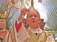 Bishop Thomas Paprocki consecrates the host during Mass.